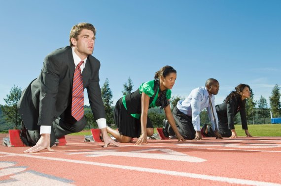Four people suited up in starting position on a track