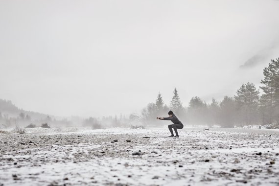 Frau macht Übungen auf einem schneebedeckten Feld.