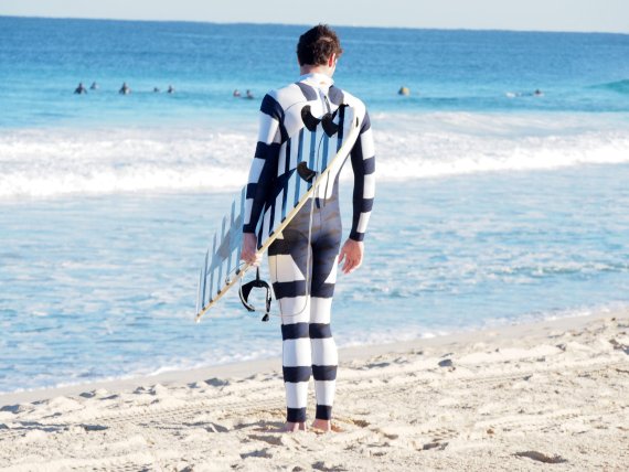 With the strips and shapes on the wetsuit and surfboard, the shark is less likely to have the surfer “for lunch.”