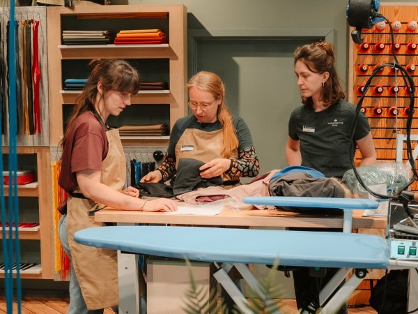 Three women stand in a Globetrotter repair workshop.