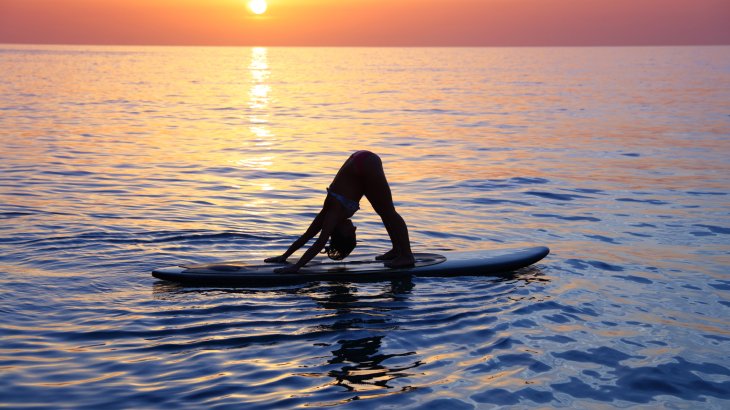 SUP-Yoga fördert die Konzentration und das Gleichgewicht. Denn hierbei werden die Übungen auf dem Wasser auf einem Surfbrett durchgeführt. Wer mit den Gedanken abschweift oder nicht bei der Sache ist, riskiert einen Fall ins kühle Nass.