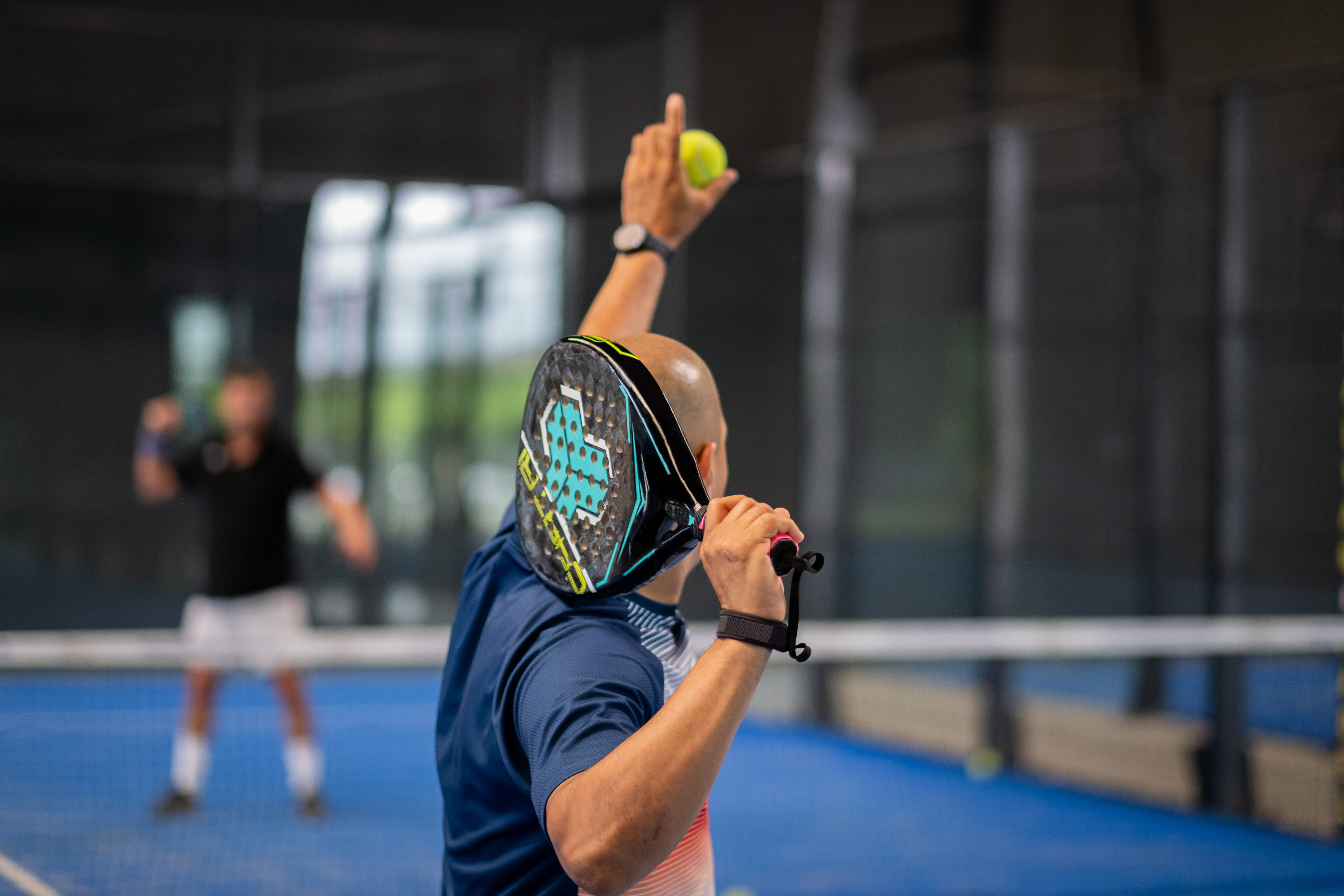 Monitor teaching padel class to man, his student - Trainer teaches boy how to play padel on indoor tennis court