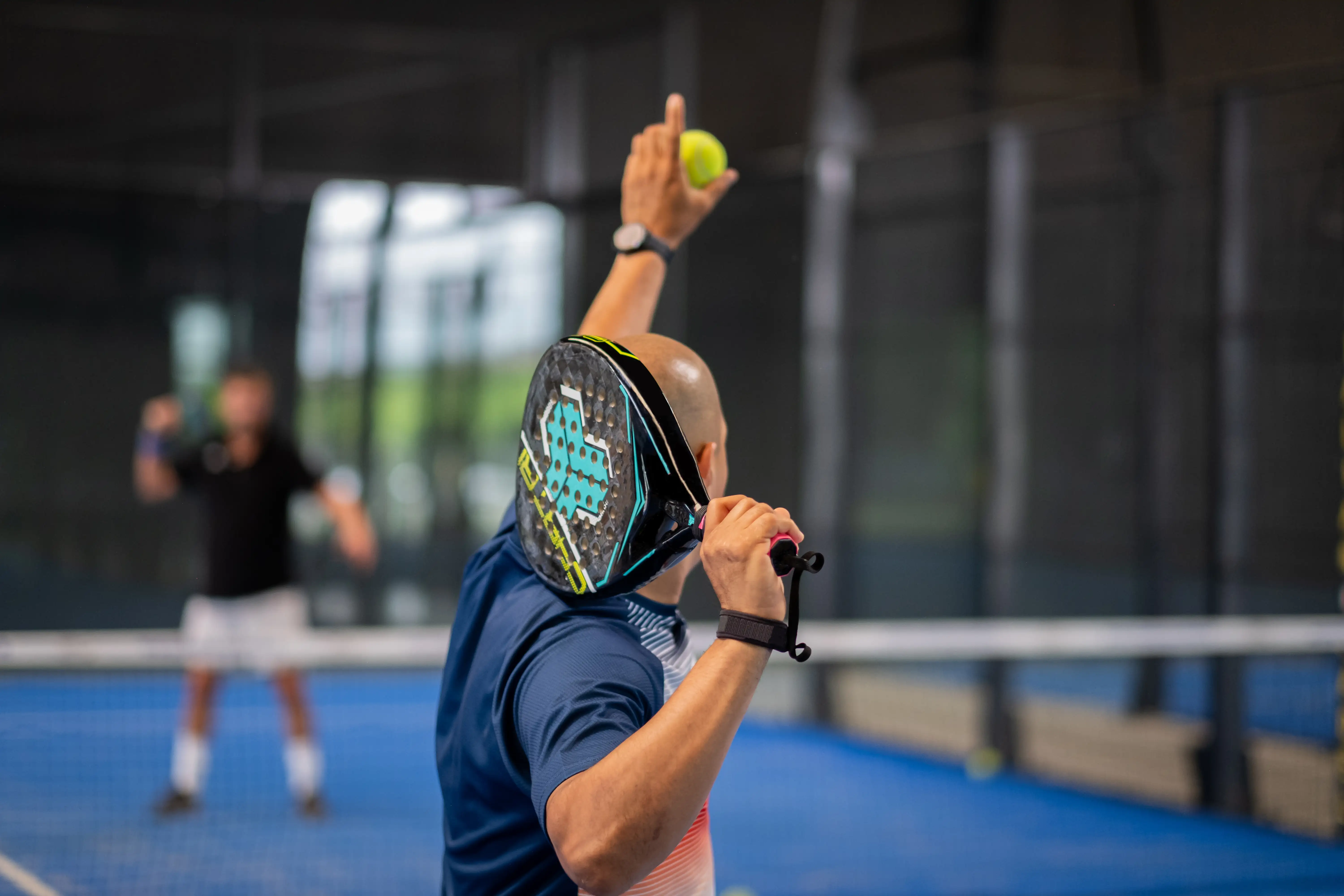 Monitor teaching padel class to man, his student - Trainer teaches boy how to play padel on indoor tennis court