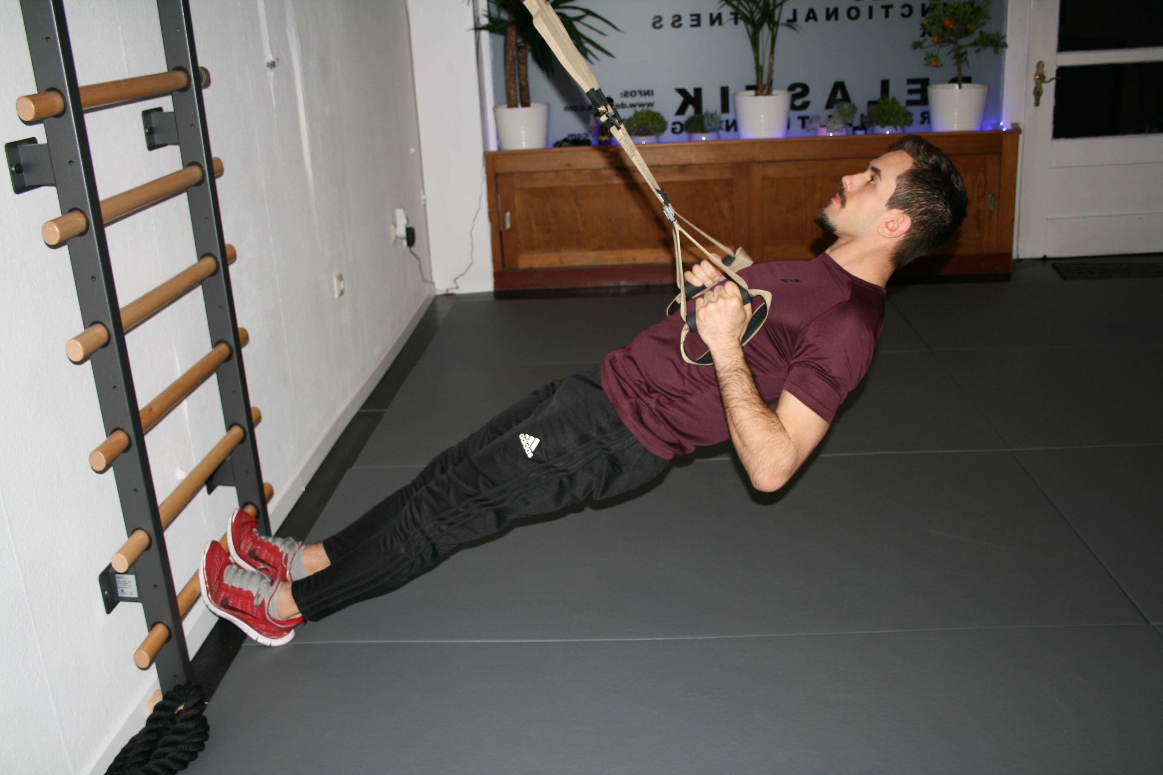 Row HIIT Übung Trainer führt einen Row mit einem Schlingentrainer aus