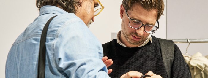 Zwei Männer auf der ISPO sprechen miteinander und betrachtet ein Produkt.