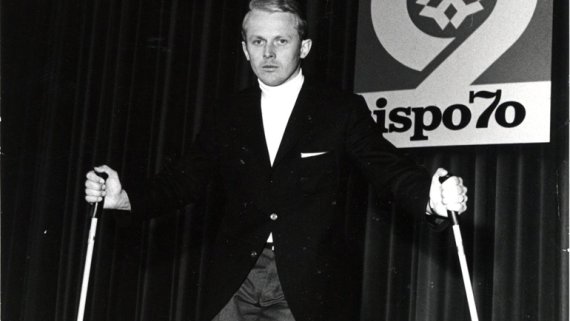 Schwarz weiß Bild von Mann mit Skistöcken auf der Bühne der ISPO 1970. 