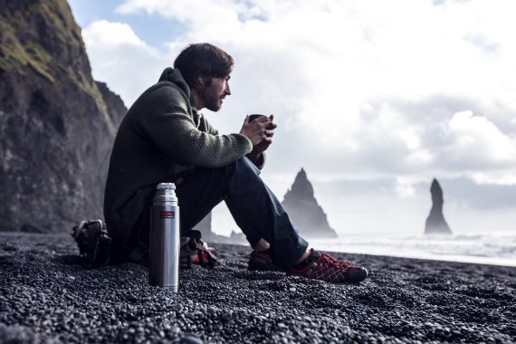 Mann wärmt sich an Thermos-Becher