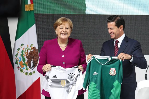 German Chancellor Angela Merkel and Mexico's President Enrique Pena Nieto with their countries' World Cup jerseys.