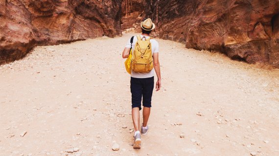 Mann spaziert am Strand mit Rucksack