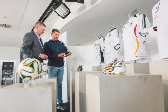 Grindel (left) and Rorsted look at a shoe and the German jerseys of the last years.