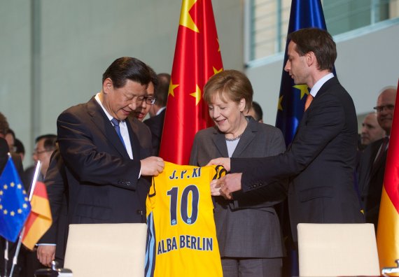 China's President Xi Jinping posing at the Berlin Chancellery wearing an ALBA Berlin jersey in 2014.
