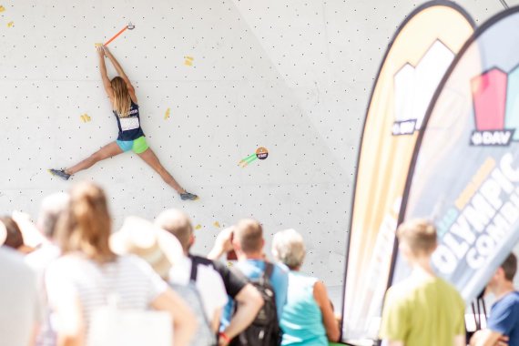 Athletin beim Bouldern Athletin beim Klettern vor einer Menschenmenge