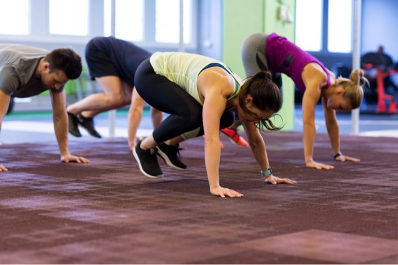 Burpees sind ideal für HIIT Eine Gruppe macht Burpees während dem HIIT