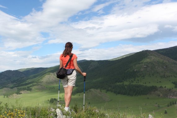 Frau steht auf einem Berg mit Nordic Walking Stöcken
