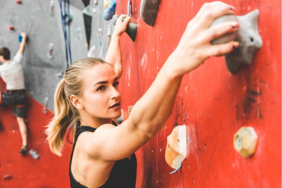 Frau klettert an einer Boulderwand Frau klettert an einer Boulderwand