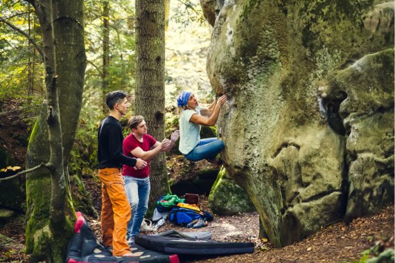 Gruppe beim Bouldern an einem Felsen im Wald