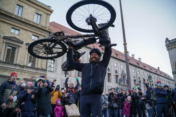 Jonas Deichmann hält sein Fahrrad triumphal in die Luft