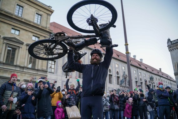 Jonas Deichmann hält sein Fahrrad triumphal in die Luft Jonas Deichmann hält sein Fahrrad triumphal in die Luft