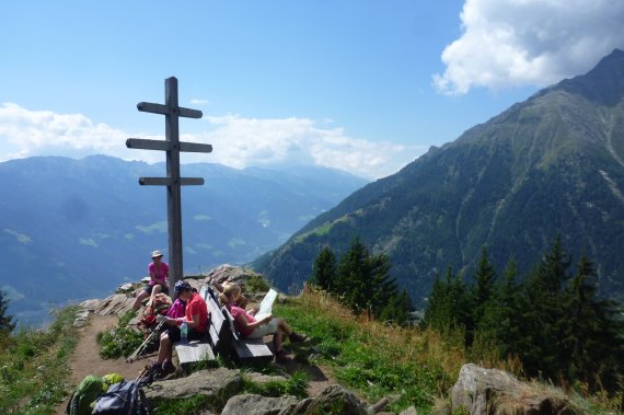 Touristen auf einem Gipfelkreuz