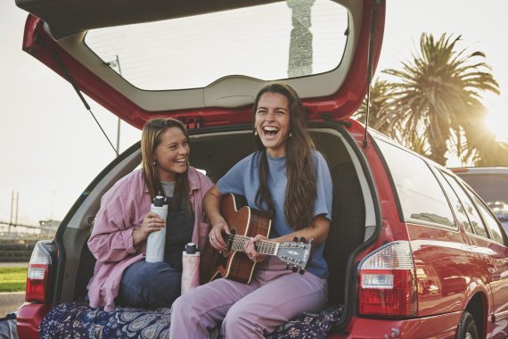 Two women sitting in trunk with guitar