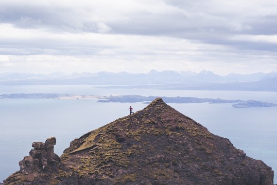 Ein Trailrunner rennt über einen Grat an einer schroffen Küstenlandschaft.