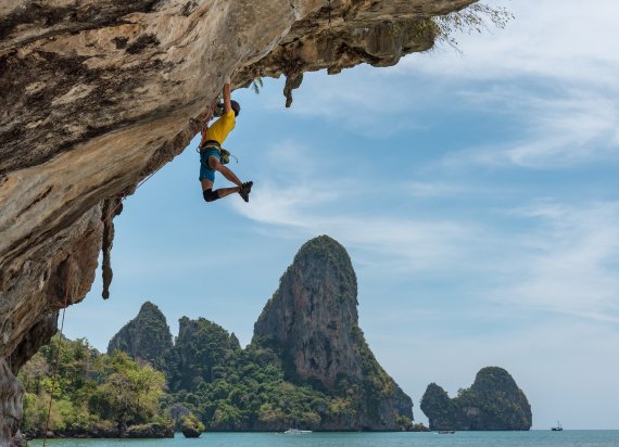 A climber hangs from a rock in Thailand.