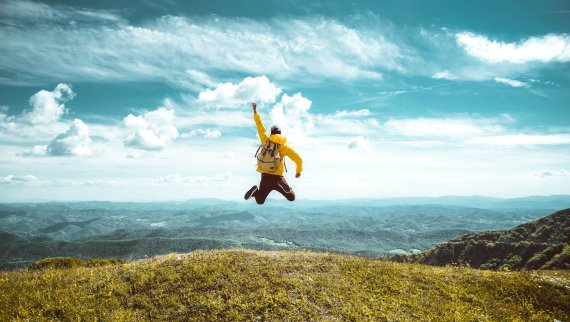 Mann mit Rucksack springt in die Luft