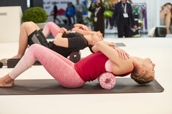 Frau nutzt eine Faszienrolle auf einer Yogamatte