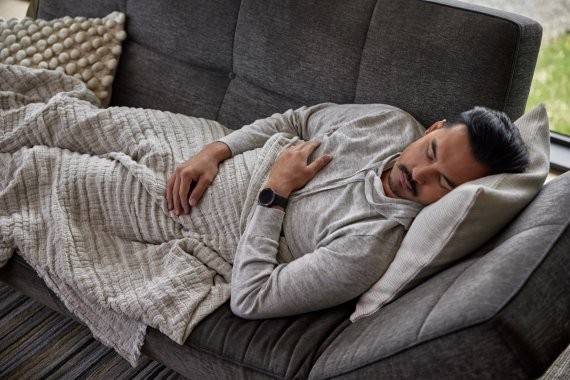 Man schläft auf Sofa mit Garmin Smartwatch