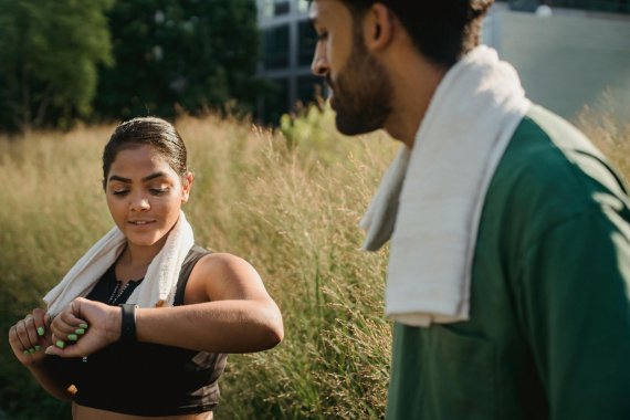 Zwei Personen machen eine Pause beim Running und schauen auf die Smartwatch