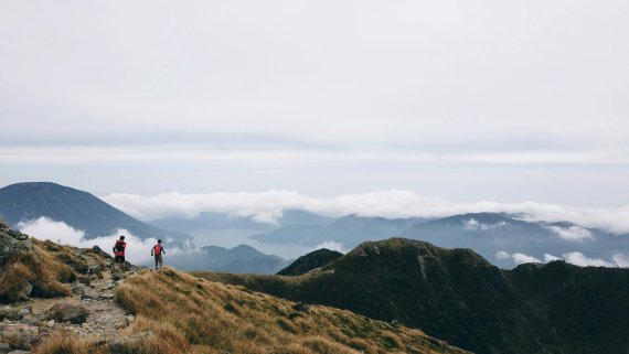 Zwei Personen in den Bergen beim Wandern mit Blick auf das Tal