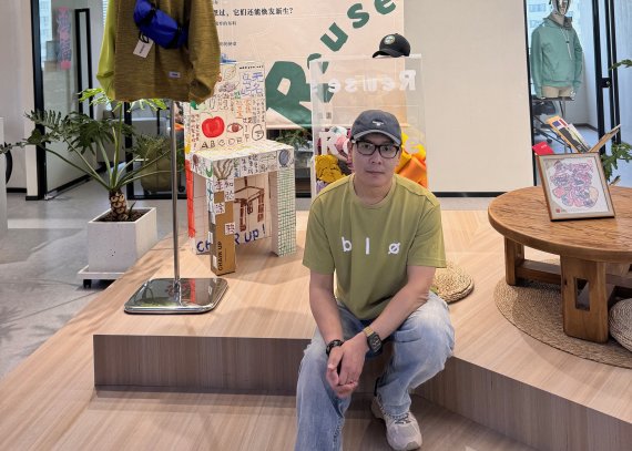 Chris Lei (Unitex) sitz in einem Store auf einer Treppe vor innovativer Outdoor-Kleidung.