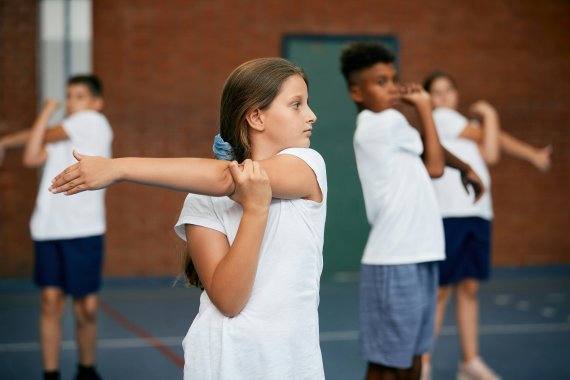 Kinder/Jugendlich wärmen sich im Sport Unterricht auf.