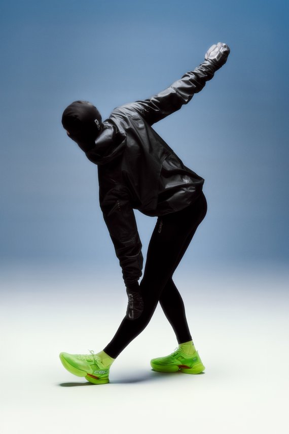 Ein Läufer in neongelben CEP Sneakern dehnt sich