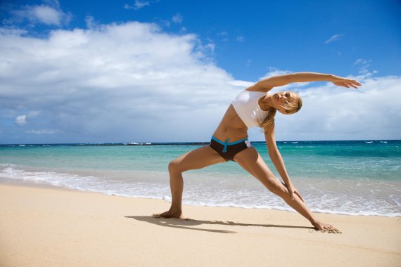 A woman does yoga on the beach.