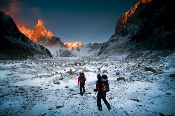 David Lama und Partner durchschreiten Bergpanorama in Abenddämmerung.