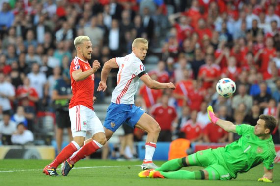 mb-160624-aaron-ramsey-fussballschuhe-euro-2016 Aaron Ramsey (l.) trägt New Balance Visaro Pro (180 Euro), Russlands Keeper Igor Akinfeev grätscht in Nike Magista Opus (200 Euro) entgegen.