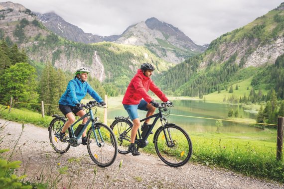 Ein paar fährt mit dem Rad an einem Seeufer entlang