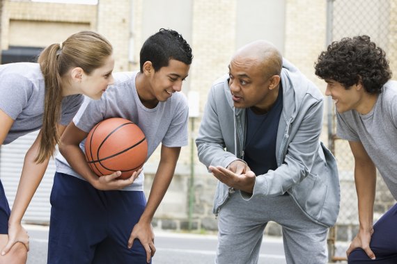Eine Frau und drei Männer sprechen nach einem Basketballspiel miteinander. 