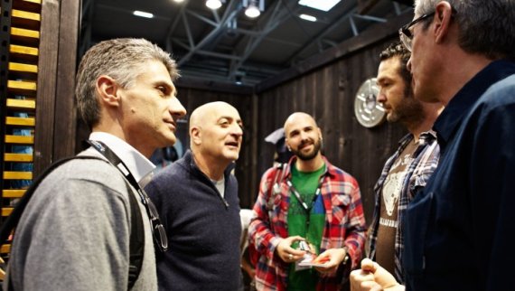 Durch Besuchereinladungen mehr Traffic am Messestand. Fünf Männer unterhalten sich vor einem Messestand der ISPO Munich.