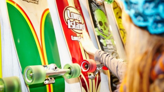Ein Frau begutachtet bunte Longboards.