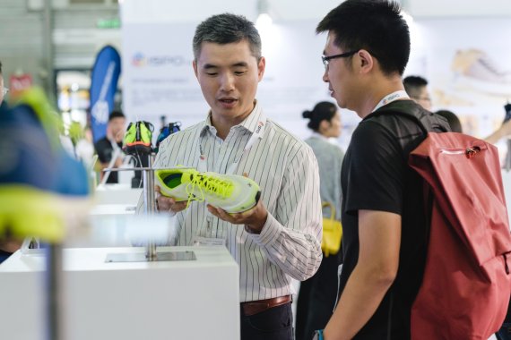 Visitors checking out new show models at the trade show Visitors having a look at yellow sports shoes