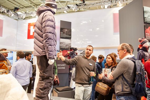 ISPO Munich: Händler im Gespräch mit Aussteller Zwei Männer betrachten Skijacke an einem Messestand