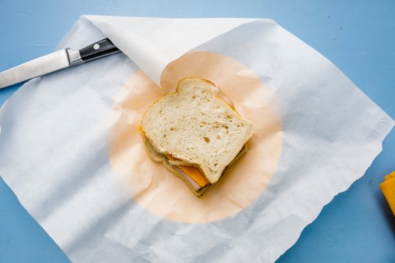 Das geschnittene Brot wird belegt und in Papier eingeschlagen 