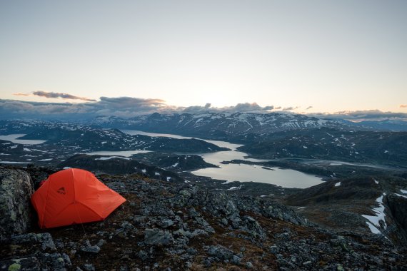 Sleeping place for the night: the orange tent on a rocky ledge 