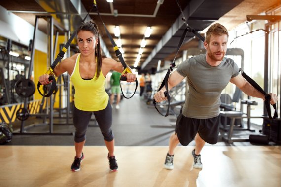 Ein Mann und eine Frau beim TRX Training mit Schlingen