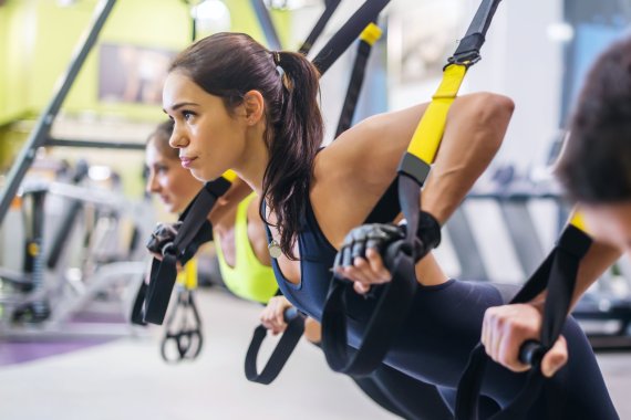 Fitness für jedermann Frau stützt sich in die Schlingen