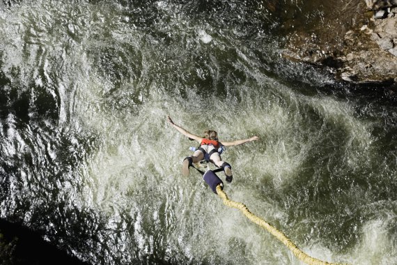mb-Die-coolsten-Bungee-Locations-der-Welt Eine Bungee-Jumperin ist von oben zu sehen, wie sie Richtung eines Gewässers hinabfällt