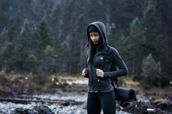 mb-freeletics_urban_ground Eine Frau steht mit einem Urban-Grounds-Hoodie im Wald