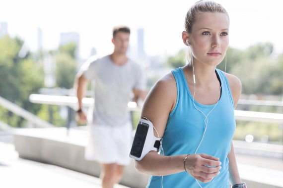 Fitnessapps beim Laufen Frau joggt mit Handy am Arm